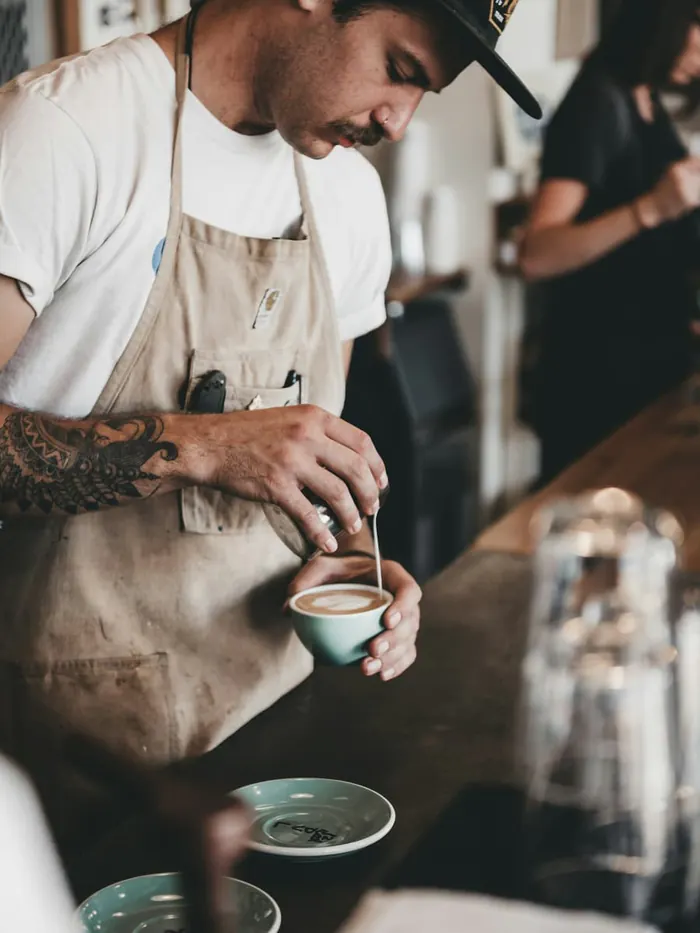 Barista tezgahın arkasında fincana süt döküyor