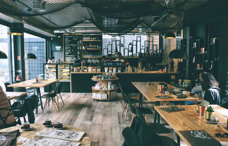 Ahşap masaların ve pencerelerin olduğu kafe salonu